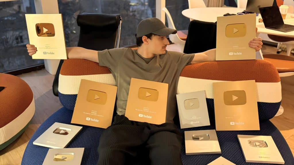Amaury Dumas entouré de plusieurs YouTube Play Buttons dorés et argentés, témoignant des succès de ses chaînes automatisées