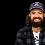 Alex Hormozi : Qui il est vraiment, sa fortune et ce qu'on peut apprendre de lui (2026) Portrait d’Alex Hormozi sur fond noir avec casquette Acquisition.com